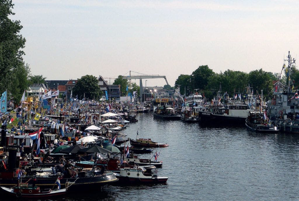 Vele boten en vlaggen in het kanaal - Stichting de Motorsleepboot