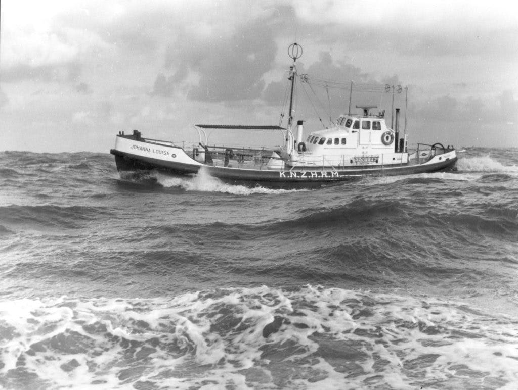 Zwart wit foto van een boot die door golven wordt belaagd